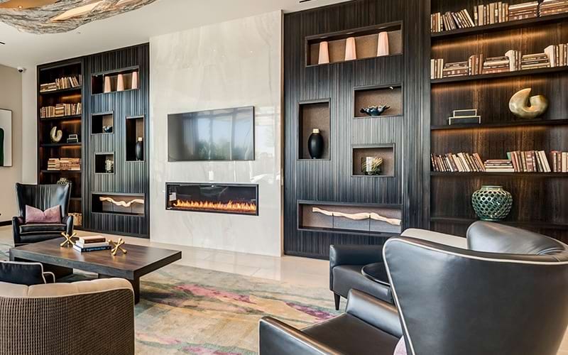 resident lounge and library area with a fireplace and warm accents with leather chairs for seating