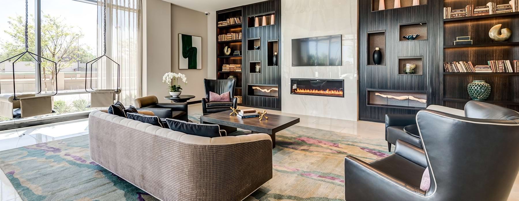 resident lounge and library area with a fireplace and warm accents with leather chairs for seating